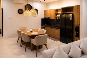 A modern kitchen with a black refrigerator, wooden cabinets, and a dining area with a wooden table and chairs. - Cala Vista Villa Tumbak Bayuh Bali. Spacious 3BR Villa for Families & Groups. (Tumbak Bayuh)