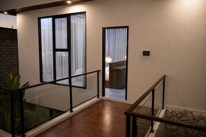 Ein modernes Interieur mit Glastrennwand, Holzboden und Wandverkleidung aus Stein.