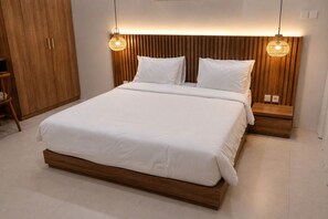 A modern bedroom with a wooden headboard, a large bed with white bedding, two bedside tables, and hanging pendant lights. - Cala Vista Villa Tumbak Bayuh Bali. Spacious 3BR Villa for Families & Groups. (Tumbak Bayuh)