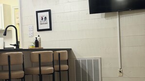 Una cocina con barra, un televisor de pantalla plana grande montado en la pared y un tapete estampado en el suelo.