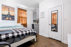 A bedroom with a bed, a desk, a mirror, and a door. - Cozy studio in peaceful Toronto perfect for your city getaway (Toronto)