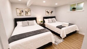 Habitación de hotel con dos camas, una mesita de noche con lámpara y obras de arte en las paredes.