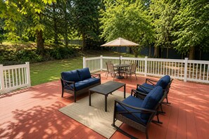 Una terraza con mobiliario exterior, una mesa y una cerca blanca.