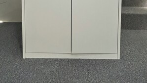 Un armario blanco con un tirador, cerca de una escalera.