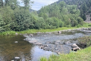 A river flowing through a forested area with rocks and greenery.