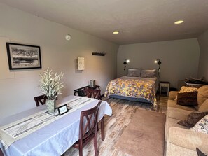 A bedroom with a bed, bedside table, lamp, and a couch.