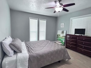 A bedroom with a bed, a dresser, a ceiling fan, and a painting on the wall. - Tranquil 3-bedroom house with AC in charming Bryan (Bryan)