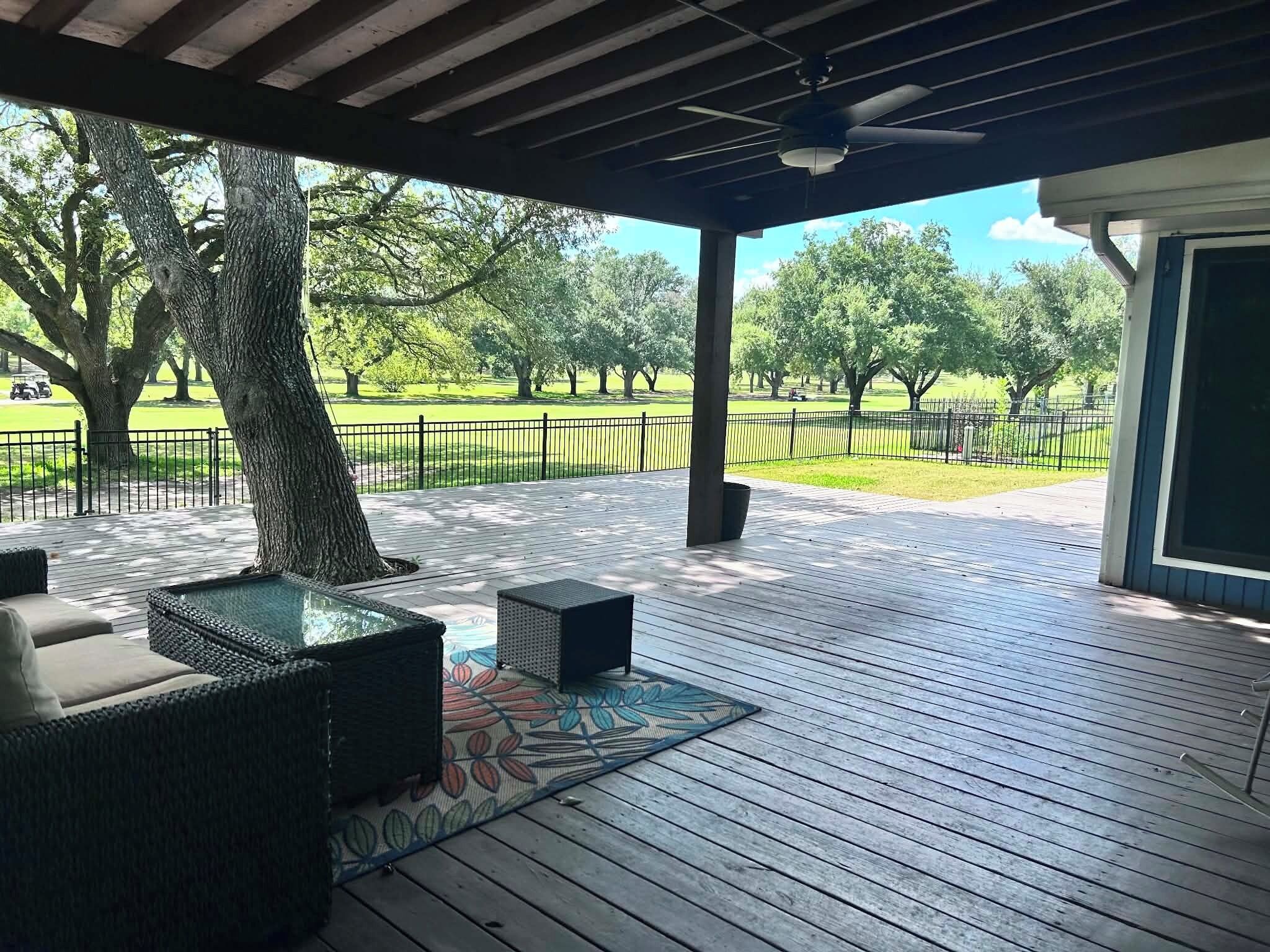 Une terrasse extérieure avec des meubles en osier et une vue sur un parc.