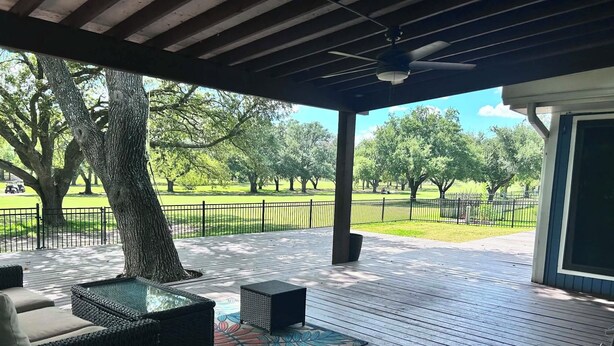 Um deck externo com móveis de vime e vista para um parque.