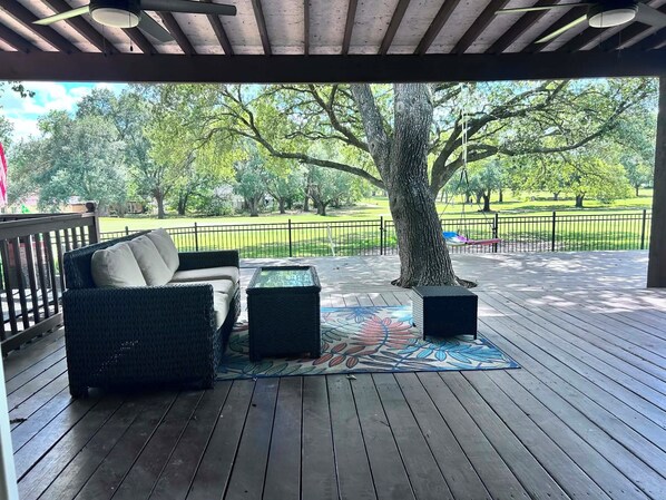 A covered outdoor seating area with a sofa, two side tables, and a patterned rug.