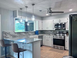 A kitchen with a marble countertop, stainless steel appliances, and pendant lighting. - Tranquil 3-bedroom house with AC in charming Bryan (Bryan)