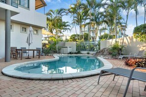 A swimming pool with lounge chairs, a table, and a covered seating area. - 14 Seashapes - Coastal Comfort With Open Spaces & Beach Glimpses (Maroochydore)