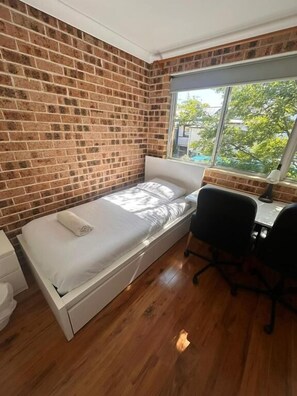 Una habitación pequeña con cama, escritorio y ventana.