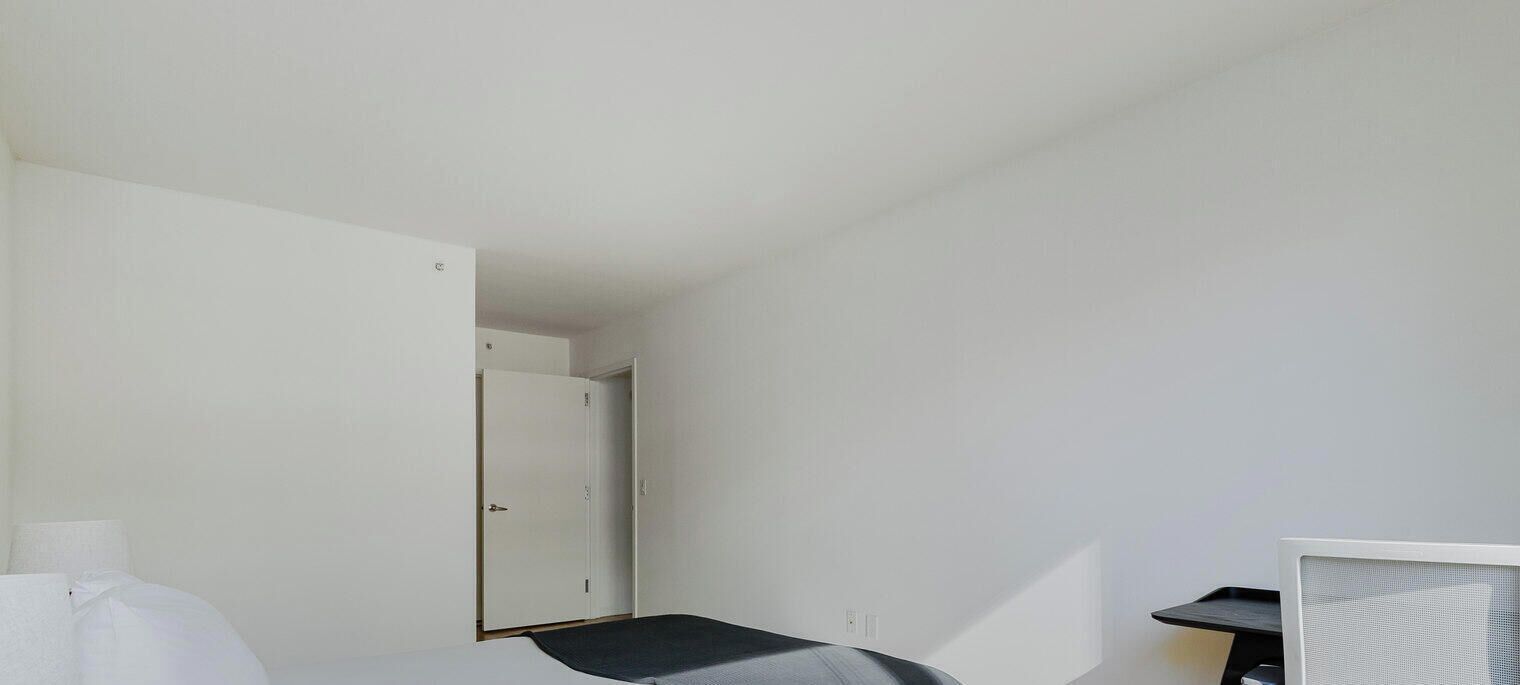 A room with a bed, a desk, and a door.