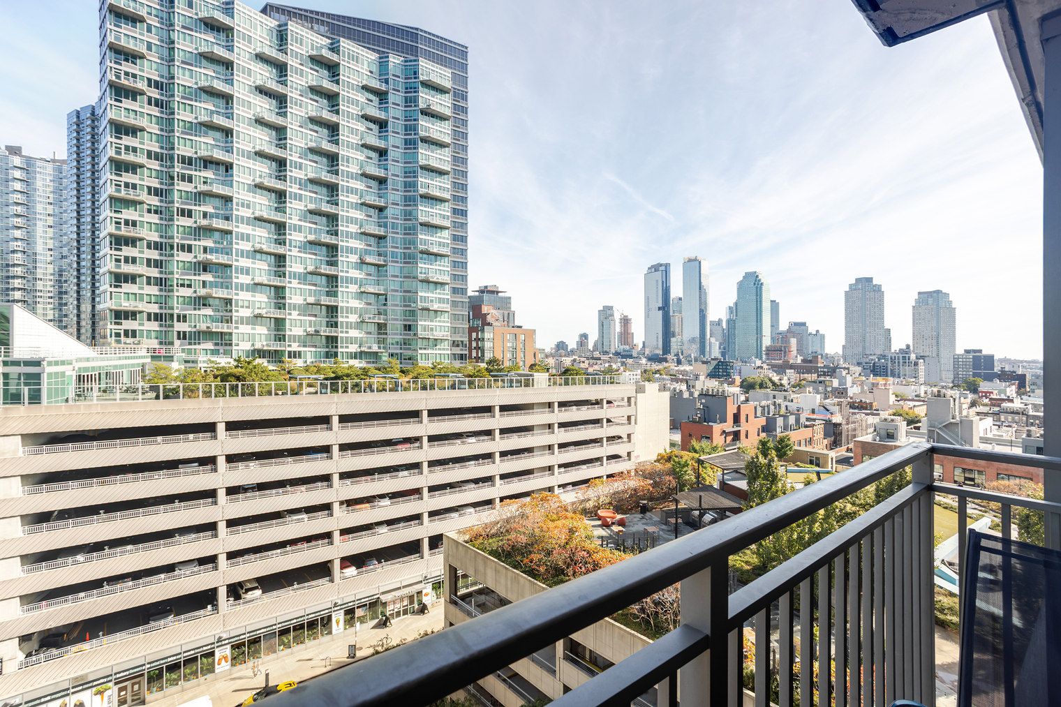 A high-rise building with multiple floors, a parking garage below, and a cityscape with various buildings in the background.