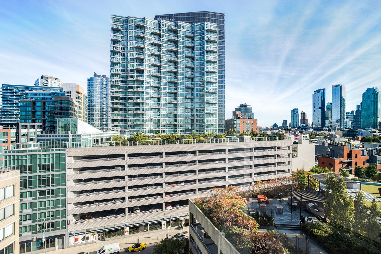 A multi-story parking garage with a modern design, surrounded by high-rise buildings and a clear sky.