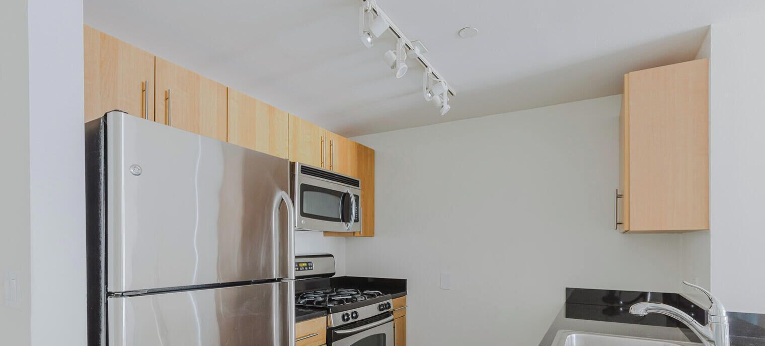 A compact kitchen with a refrigerator, microwave, stove, and sink.