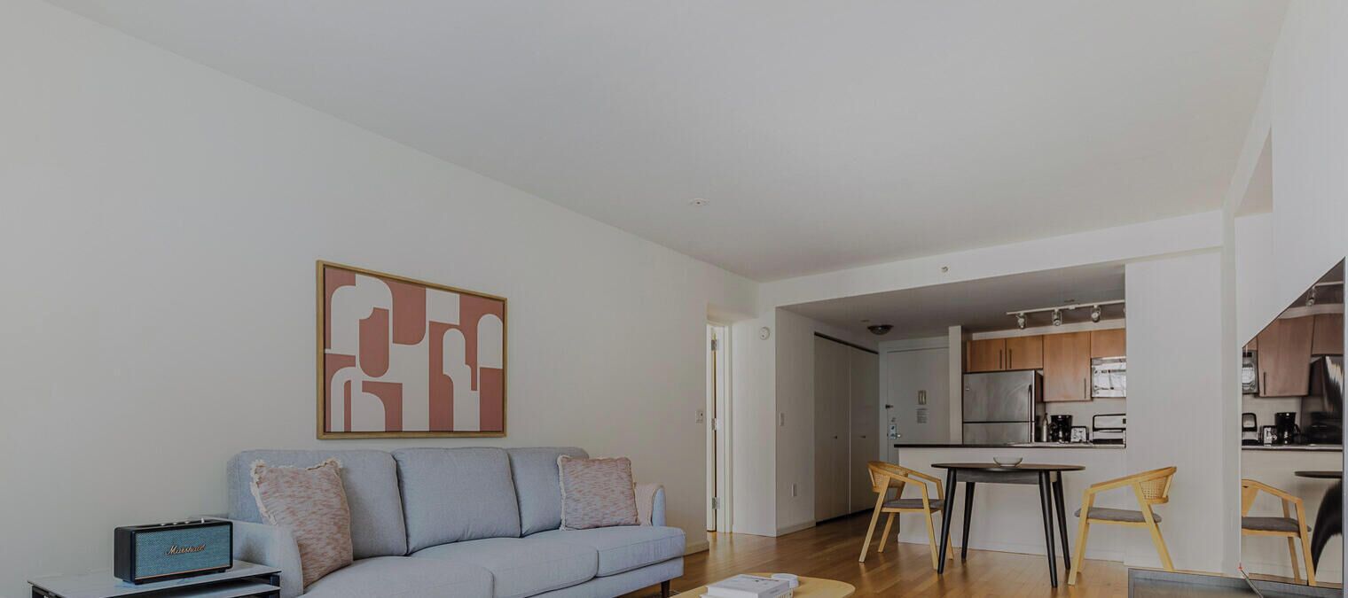 A modern living room with a sofa, a coffee table, and a kitchen in the background.