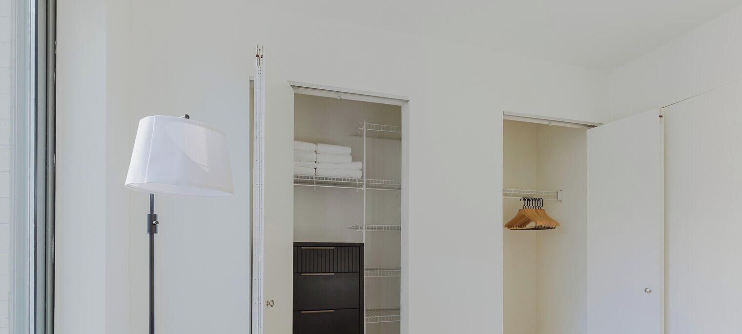 A closet with shelves, a hanging rack, and a lamp.