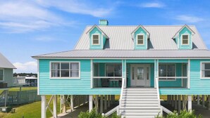 A two-story house with a front porch and a staircase leading to the entrance. - Little Lagoon Waterfront • Private Pier • West Beach •  Dockside Oasis by Kaiser (Gulf Shores)