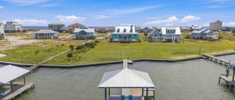 Una zona residencial costera con casas, un muelle y un campo cubierto de hierba.