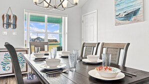 A dining area with a wooden table set for four, chairs, and a view of the outside. - Little Lagoon Waterfront • Private Pier • West Beach •  Dockside Oasis by Kaiser (Gulf Shores)