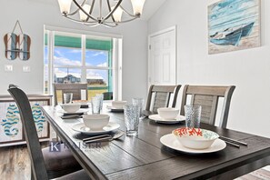 A dining area with a wooden table set for four, chairs, and a view of the outside. - Little Lagoon Waterfront • Private Pier • West Beach •  Dockside Oasis by Kaiser (Gulf Shores)
