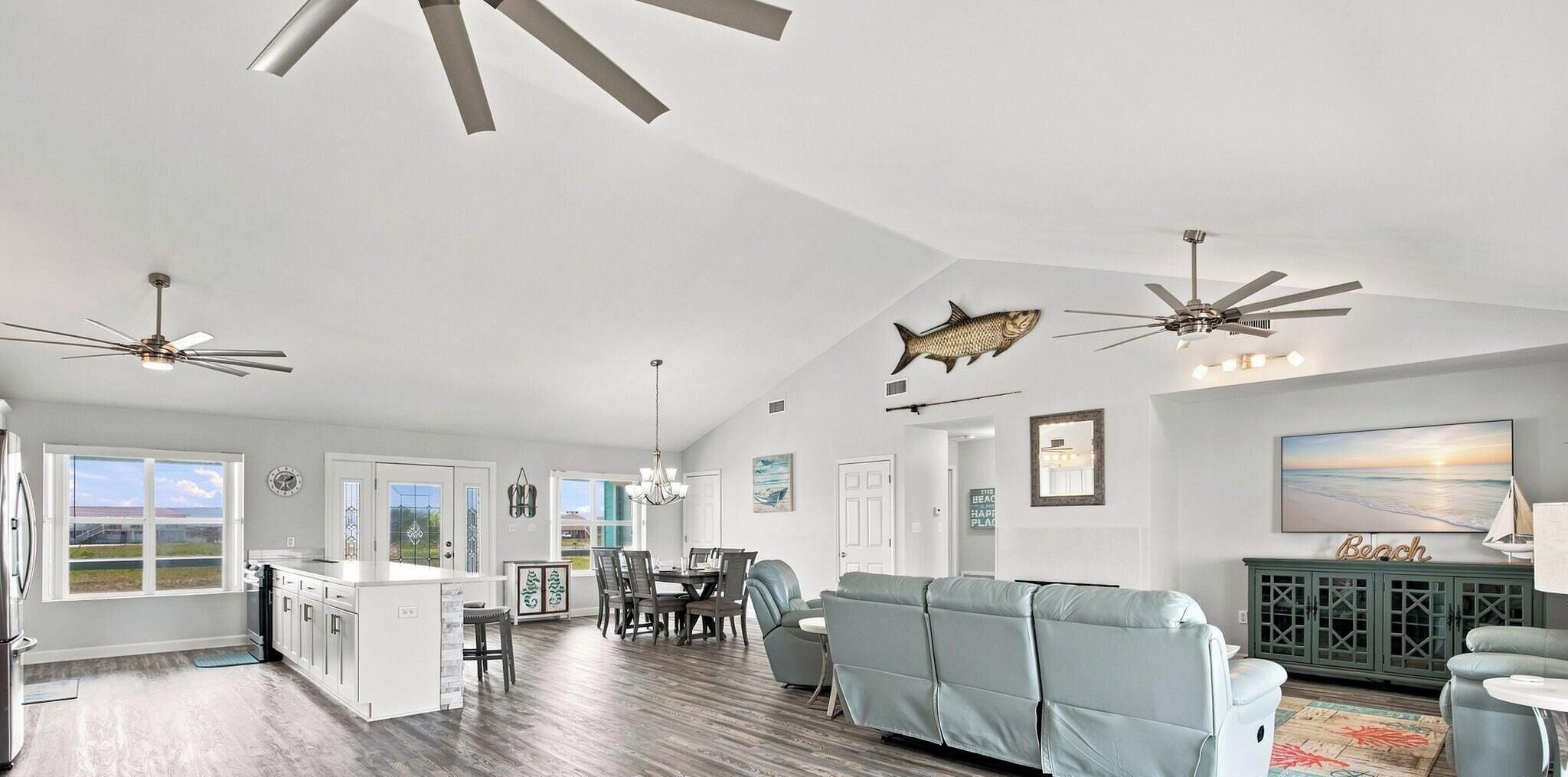 A spacious living area with a dining table, a sofa, and ceiling fans.