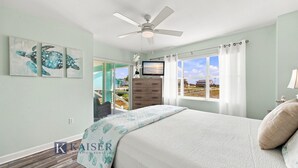 A bedroom with a bed, a ceiling fan, a TV, and a window with curtains. - Little Lagoon Waterfront • Private Pier • West Beach •  Dockside Oasis by Kaiser (Gulf Shores)