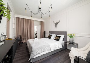 A modern bedroom with a bed, bedside tables, a desk, and a chandelier. - Nowolipie Cozy Haven Studio (Warszawa)