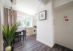 Eine moderne Küche mit Waschmaschine, Essbereich mit Tisch und Stühlen sowie ein großes Fenster mit Vorhängen.