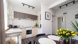 Une cuisine moderne avec des meubles blancs, une cuisinière et un coin repas comprenant une table et des chaises.