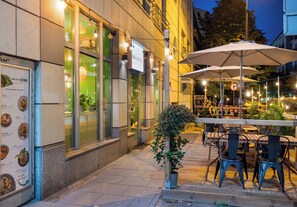 An outdoor dining area with tables and chairs, a sign for a restaurant, and a potted plant. - Hoża Artistic Charm Studio (Warszawa)