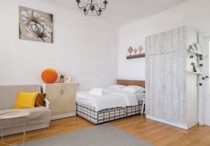 A bedroom with a bed, a sofa, a wardrobe, and a painting on the wall. - Hoża Artistic Charm Studio (Warszawa)