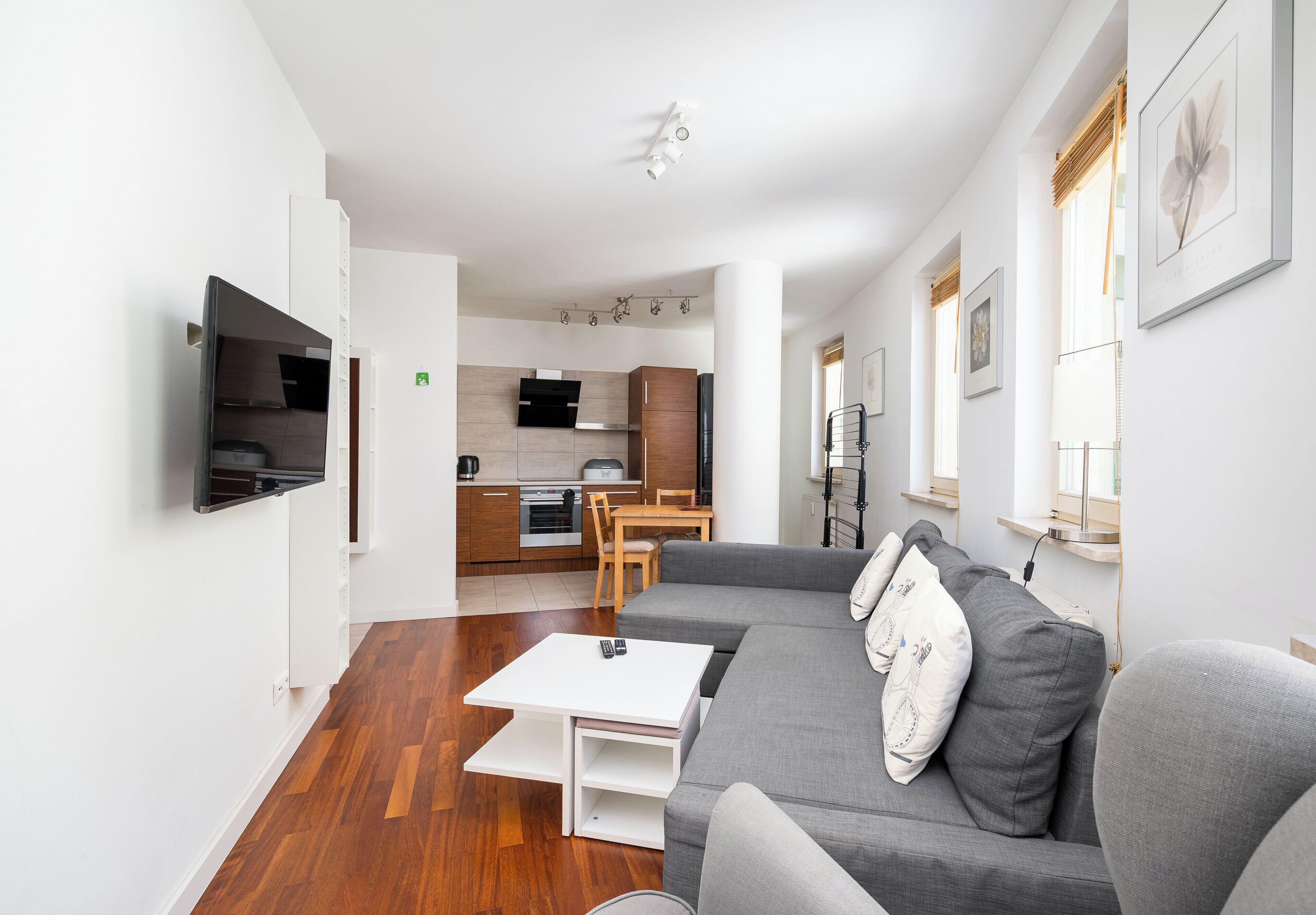 A modern living room with a grey sofa, a coffee table, and a TV mounted on the wall.