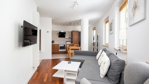Ein modernes Wohnzimmer mit grauem Sofa, Couchtisch und Wandfernseher.