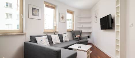 Una sala de estar moderna con un sofá gris, una mesa de centro y un televisor montado en la pared.