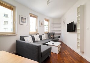Un salon moderne avec un canapé gris, une table basse et un téléviseur fixé au mur.