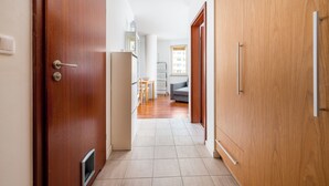 Ein Flur mit Holztüren, einer weißen Wand und einem gefliesten Boden.