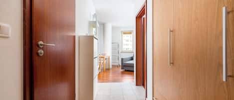 Un pasillo con puertas de madera, una pared blanca y un suelo de baldosas.