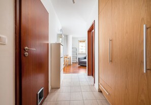 Ein Flur mit Holztüren, einer weißen Wand und einem gefliesten Boden.