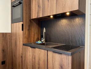 Eine Küche mit Einbauherd, einem modernen Wasserhahn und Holzschränken.