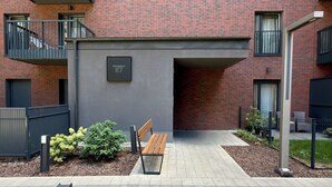 A modern building with a brick facade, a bench, and a small garden area. - Madalińskiego Modern Studio 8B (Wrocław)