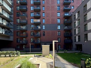 A multi-story residential building with balconies, a paved courtyard, and a small garden area. - Madalińskiego Modern Studio 8A (Wrocław)