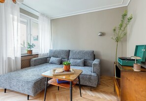 A modern living room with a grey sofa, a wooden coffee table, and a potted plant. - Szczecin City Center Apartment (Szczecin)