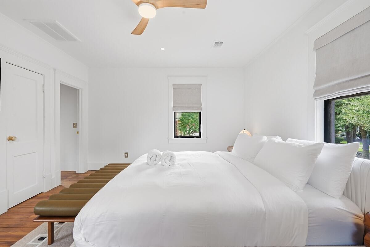 A bedroom with a large bed, a wooden headboard, a window with a view, and a staircase.