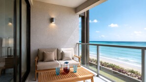 Ein Balkon mit einer Couch, einem Tisch und Blick aufs Meer.