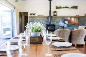 A dining table set with plates and glasses, a potted plant, and a fireplace in the background. - Greystoke Lodge - Dalefield (Dalefield)
