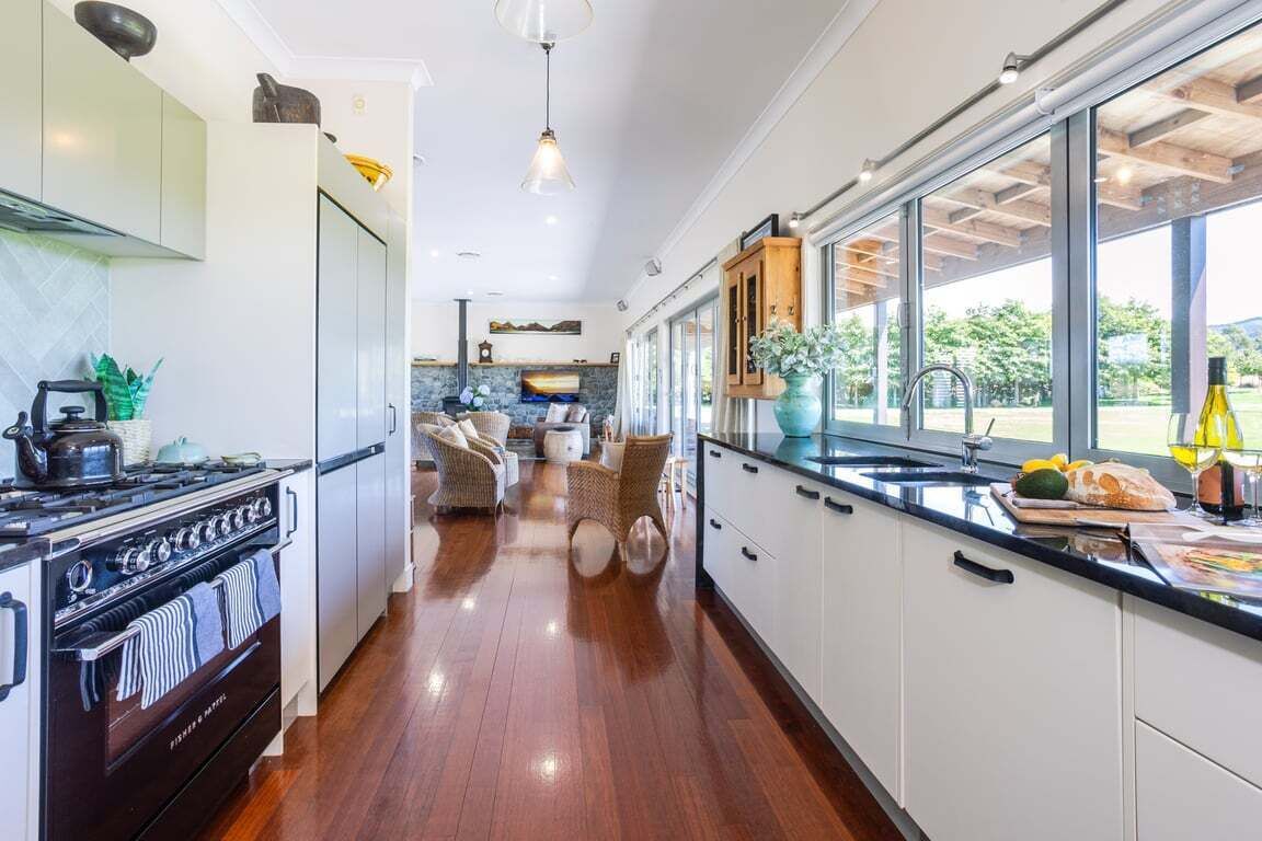 Una cucina moderna con isola centrale, pavimento in legno e vista panoramica attraverso ampie finestre.