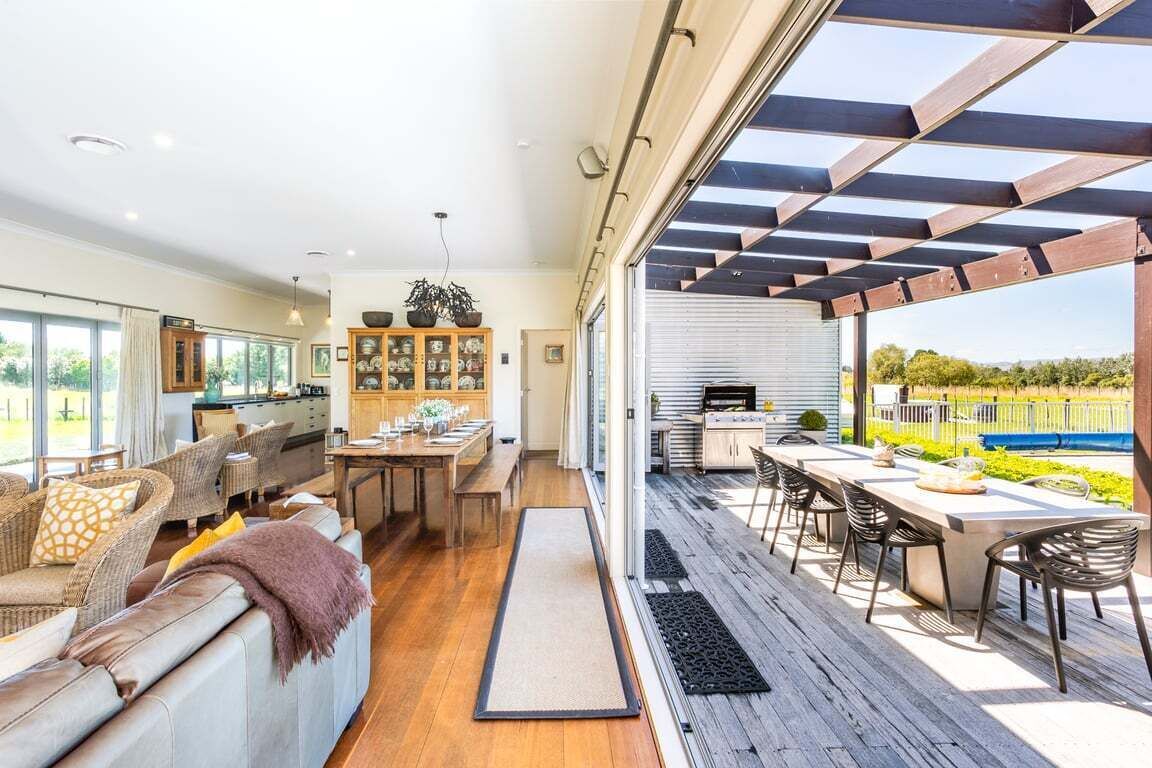 A spacious living area with a dining table, sofas, and a kitchen area with a pergola.